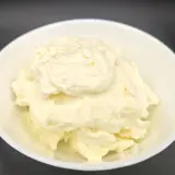 Un cremoso mascarpone fatto in casa con latte, servito in una ciotola bianca. La sua consistenza morbida e invitante promette delizie culinarie.