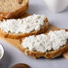 Fette di pane rustico con abbondante ricotta fresca, pronte per gustose ricette con ricotta.