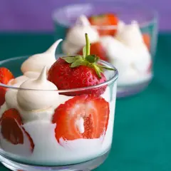 Coppette di fragole e gelato alla panna, guarnite con meringhe.