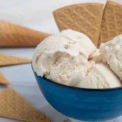 Coppetta blu con gelato fiordilatte cremoso, circondata da coni e cialde. Gli ingredienti base per un piacere semplice.