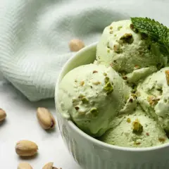 Coppa di gelato al pistacchio fatto in casa da Benedetta, guarnita con pistacchi tritati e foglioline di menta.