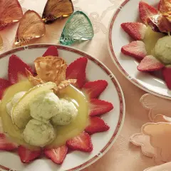Delizioso sorbetto di mela servito con fragole fresche e una cialda croccante.