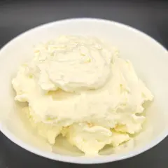 Un cremoso mascarpone fatto in casa con latte, servito in una ciotola bianca. La sua consistenza morbida e invitante promette delizie culinarie.