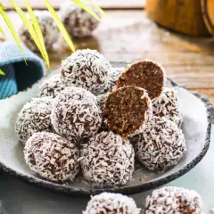 Un piatto pieno di golose palline di cocco, alcune intere, altre tagliate a metà per mostrare il ripieno scuro e invitante.