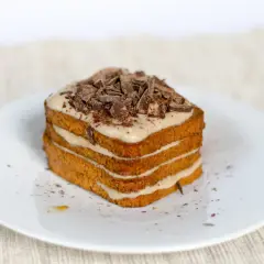 Una deliziosa torta tiramisù a più strati, ricoperta di crema e scaglie di cioccolato fondente.