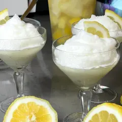 Tre coppe di granita al limone, guarnite con fette di limone, pronte per essere gustate. La ricetta granita al limone è perfetta per rinfrescarsi.