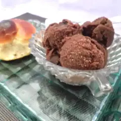 Un dolce pane intrecciato accanto a una coppa di granita cioccolato, serviti su un piatto di vetro.