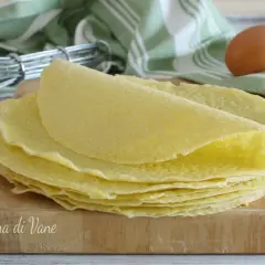 Una pila di crepes dorate su un tagliere di legno, pronte per essere farcite. La ricetta crepes perfetta per ogni occasione.