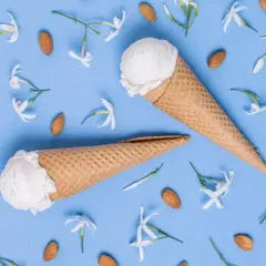 Due coni gelato al gelsomino, circondati da mandorle e delicati fiori bianchi su sfondo azzurro.