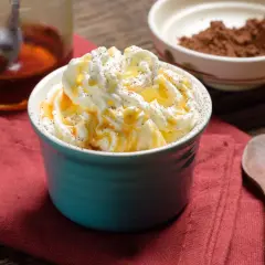 Dolcezza cremosa: cos'è heavy cream? Panna montata soffice, caramello dorato e una spolverata di cacao su un tavolo rustico.