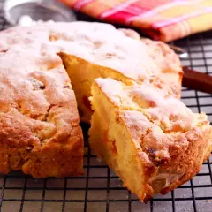 Una fetta di torta albicocche, cosparsa di zucchero a velo, riposa su una griglia.