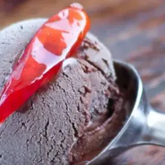 Un cucchiaio di gelato al cioccolato con una decorazione di peperoncino rosso lucido. Un'esplosione di dolcezza e piccantezza.