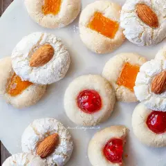 Biscotti con mandorle e marmellata, alcuni spolverati di zucchero a velo, ricordano un delizioso sorbetto alla mandorla.
