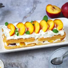 Delizioso tiramisù alle pesche, con strati di savoiardi, crema soffice e pesche fresche, guarnito con menta.