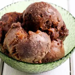 Coppa di sorbetto al cioccolato, con palline scure e invitanti, servite in una ciotola verde smeraldo.