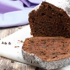 Plumcake al cioccolato soffice e goloso, spolverato di zucchero a velo, con gocce di cioccolato visibili.