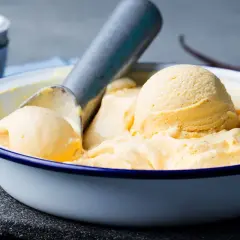 Ciotola di gelato alla vaniglia fatto in casa, con palline cremose e un mestolo. Perfetto per una calda giornata estiva.