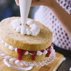 Decorazione di una torta con panna fresca montata. La differenza tra panna fresca e panna da cucina è evidente nella consistenza e nel risultato finale.