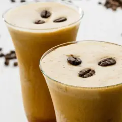 Due bicchieri di cremoso sorbetto al caffè, guarniti con chicchi tostati, invitano a una pausa rinfrescante.