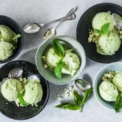 Coppette di gelato al basilico, guarnite con foglioline fresche e pezzetti croccanti. Un gusto inaspettato e rinfrescante.