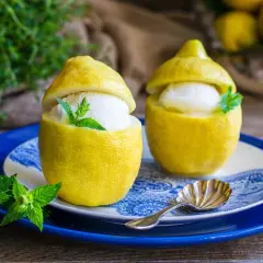 Due deliziosi gelati al limone serviti in limoni svuotati, guarniti con menta fresca. Un dessert rinfrescante e veloce.