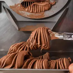 Gelato al cioccolato cremoso viene prelevato da una macchina, con destrosio additivo per la consistenza perfetta.