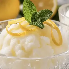 Sorbetto al limone con gelato, guarnito con scorza di limone e menta, in una coppetta di cristallo.