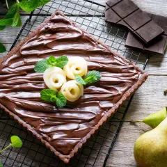Torta quadrata al cioccolato con pere a rosa e menta. Un dolce goloso che unisce la cremosità della ricotta, la dolcezza delle pere e l'intensità del cioccolato.