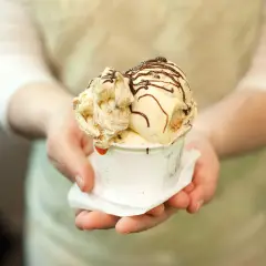 Un cono di gelato artigianale, con variegature e scaglie di cioccolato, pronto per essere gustato, un assaggio della storia del gelato.
