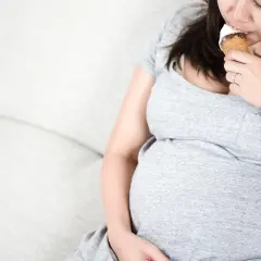 Donna incinta si gode un cono gelato, pensando a quali gusti scegliere.