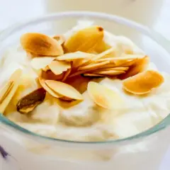Deliziosa granita di mandorle in un bicchiere, guarnita con mandorle tostate a lamelle.