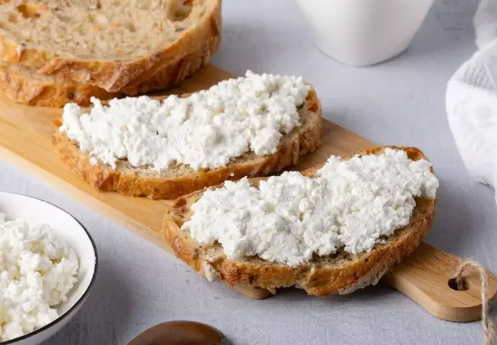 Fette di pane rustico con abbondante ricotta fresca, pronte per gustose ricette con ricotta.