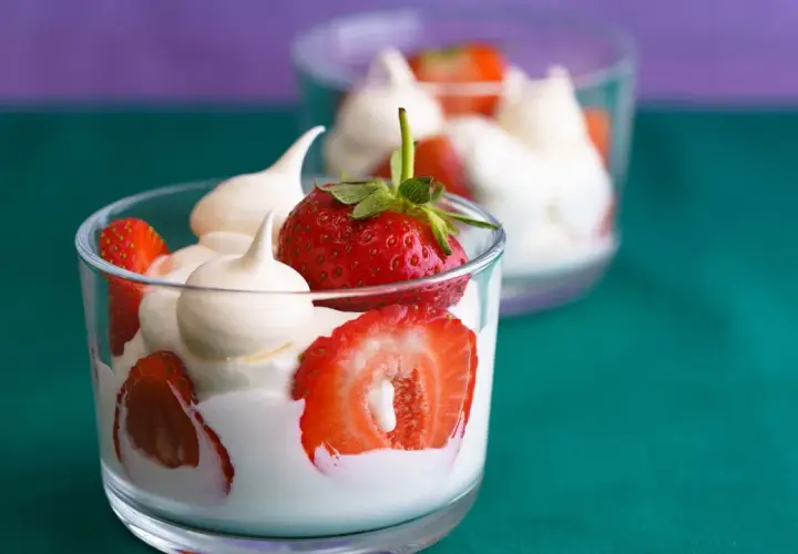 Coppette di fragole e gelato alla panna, guarnite con meringhe.
