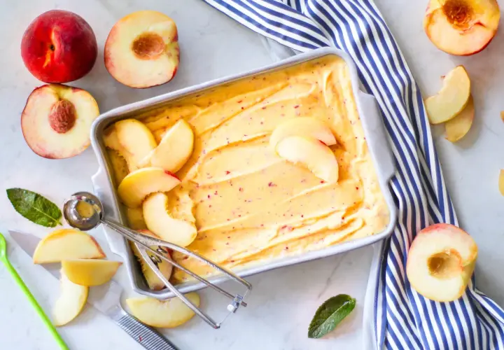 Sorbetto alla pesca fatto in casa, con pesche fresche e un cucchiaio per servirlo. Un dolce estivo rinfrescante.