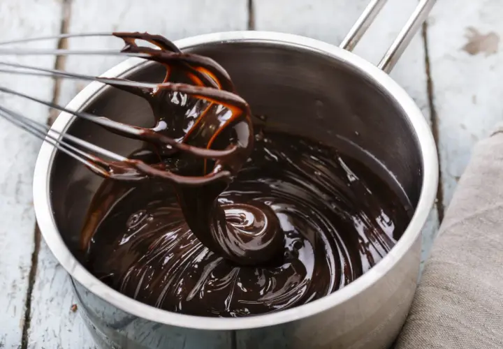 Cioccolato fuso lucido e cremoso in una pentola, pronto per essere usato. Scopri come mantenere liquido il cioccolato sciolto per dolci perfetti.