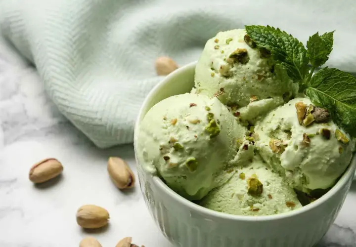 Coppa di gelato al pistacchio fatto in casa da Benedetta, guarnita con pistacchi tritati e foglioline di menta.