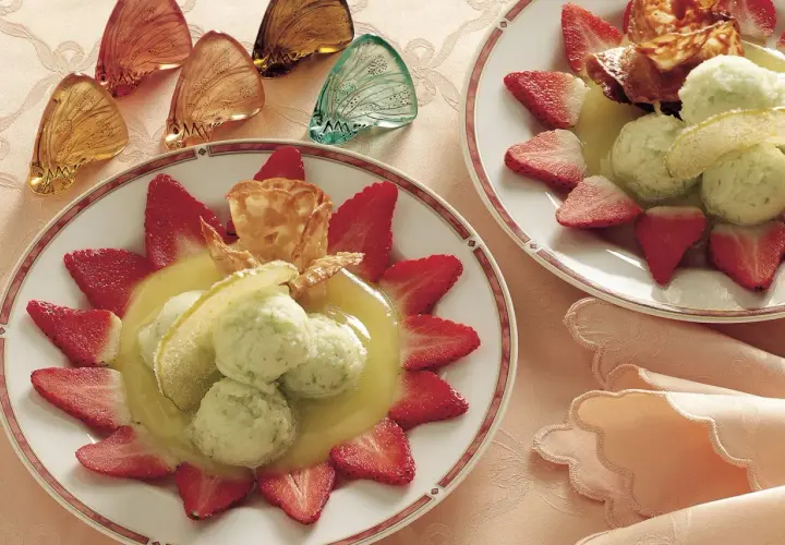 Delizioso sorbetto di mela servito con fragole fresche e una cialda croccante.