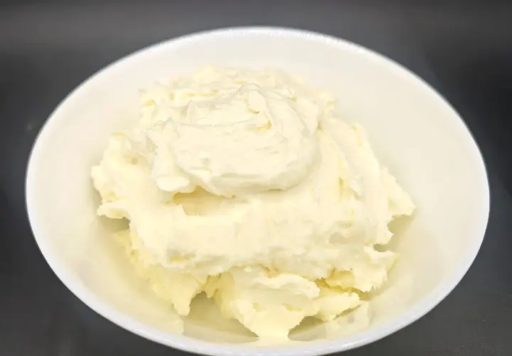 Un cremoso mascarpone fatto in casa con latte, servito in una ciotola bianca. La sua consistenza morbida e invitante promette delizie culinarie.