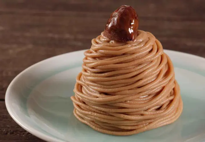 Un delizioso montblanc dolce, un dolce di castagne a forma di cono, guarnito con una castagna lucida.