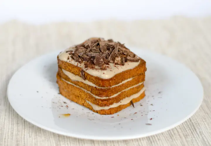 Una deliziosa torta tiramisù a più strati, ricoperta di crema e scaglie di cioccolato fondente.