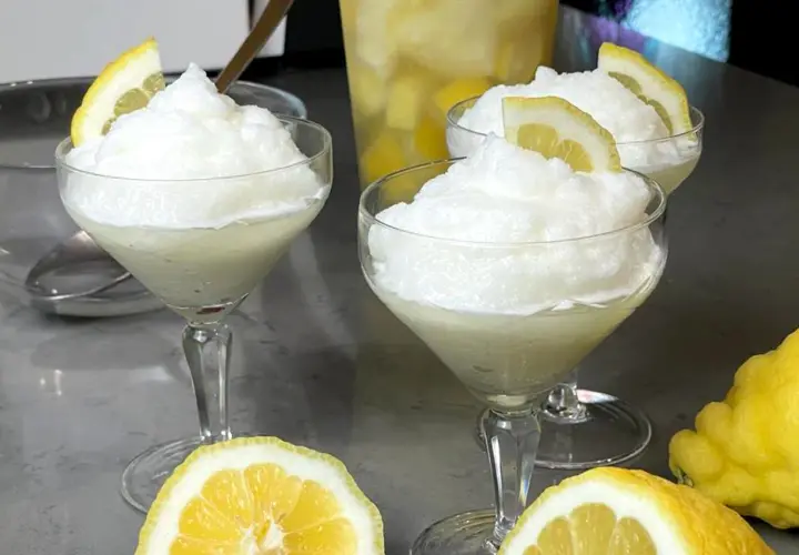 Tre coppe di granita al limone, guarnite con fette di limone, pronte per essere gustate. La ricetta granita al limone è perfetta per rinfrescarsi.