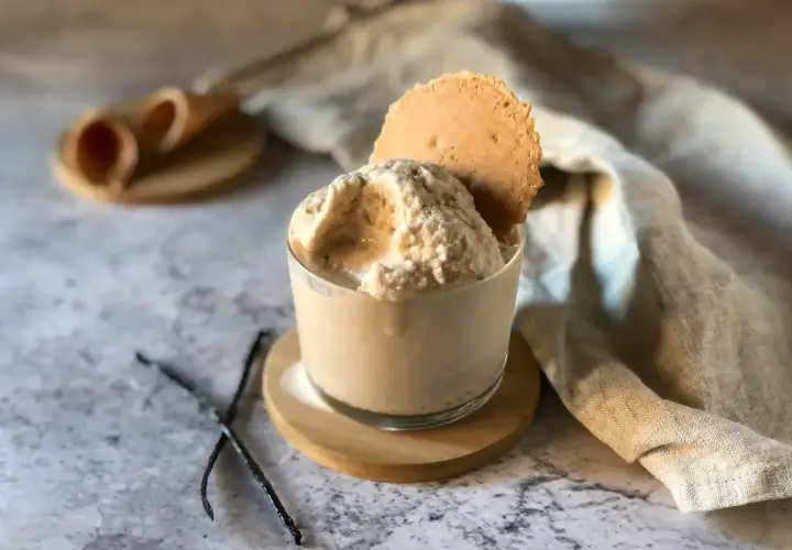 Delizioso gelato con panna vegetale, guarnito con un biscotto croccante e bacche di vaniglia.