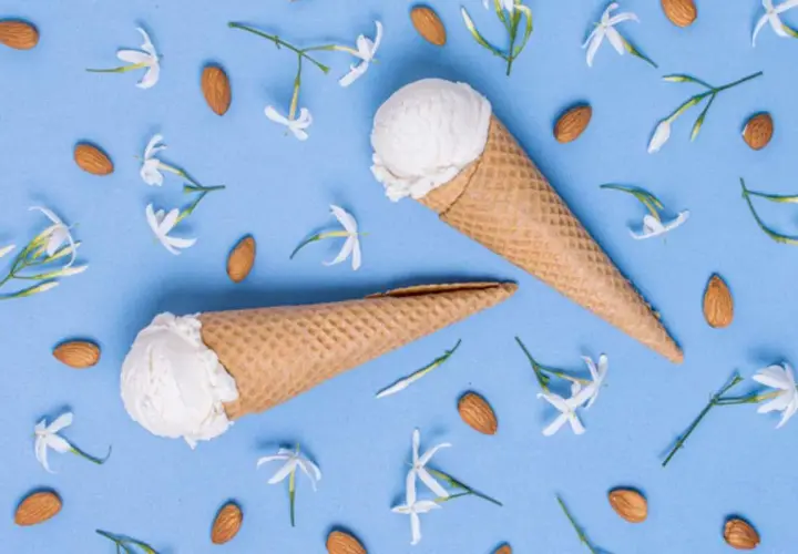Due coni gelato al gelsomino, circondati da mandorle e delicati fiori bianchi su sfondo azzurro.