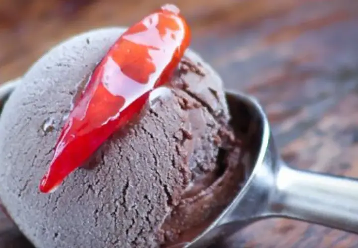 Un cucchiaio di gelato al cioccolato con una decorazione di peperoncino rosso lucido. Un'esplosione di dolcezza e piccantezza.