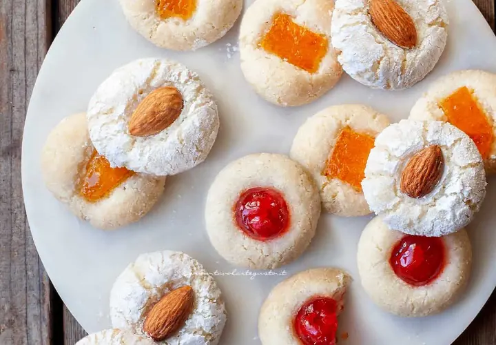 Biscotti con mandorle e marmellata, alcuni spolverati di zucchero a velo, ricordano un delizioso sorbetto alla mandorla.