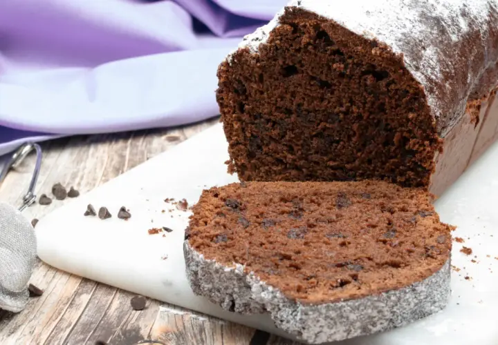 Plumcake al cioccolato soffice e goloso, spolverato di zucchero a velo, con gocce di cioccolato visibili.