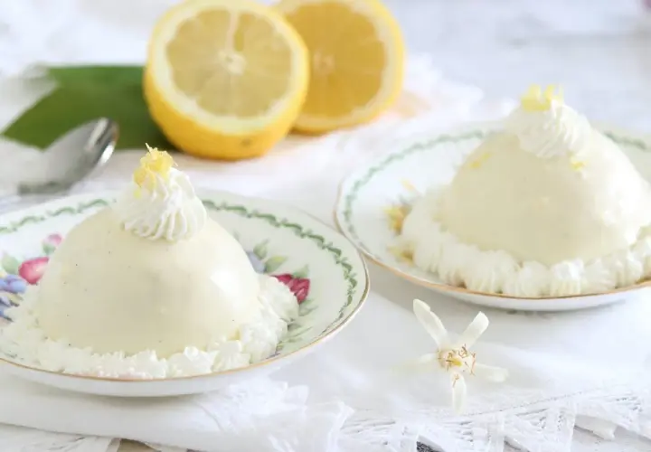 Deliziose delizie al limone, dolci cremosi su piattini fioriti, guarniti con panna e scorza di limone.