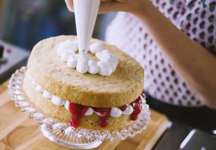 Decorazione di una torta con panna fresca montata. La differenza tra panna fresca e panna da cucina è evidente nella consistenza e nel risultato finale.