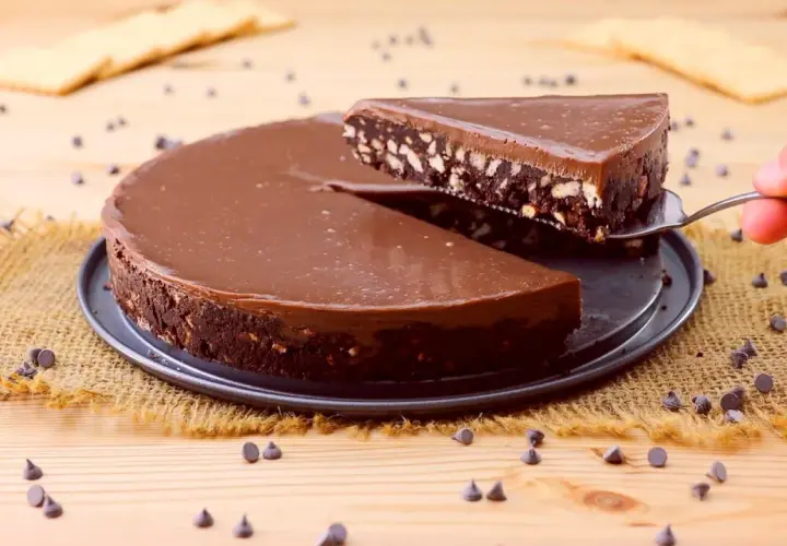 Una fetta di torta fredda con biscotti e cioccolato viene sollevata da una tortiera.