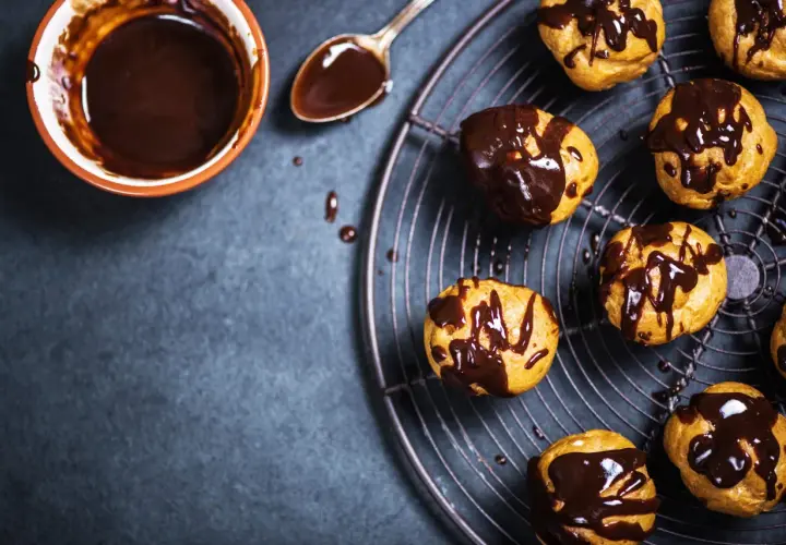 Profitterol ricetta: bignè dorati glassati con cioccolato fuso, pronti per essere gustati.